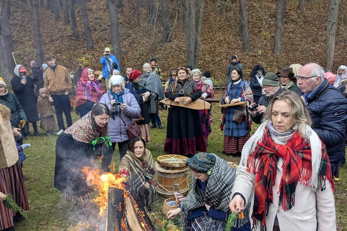 Besökare i folkdräkt runt en Mārtiņdiena-brasa på Lettlands etnografiska friluftsmuseum, Riga.