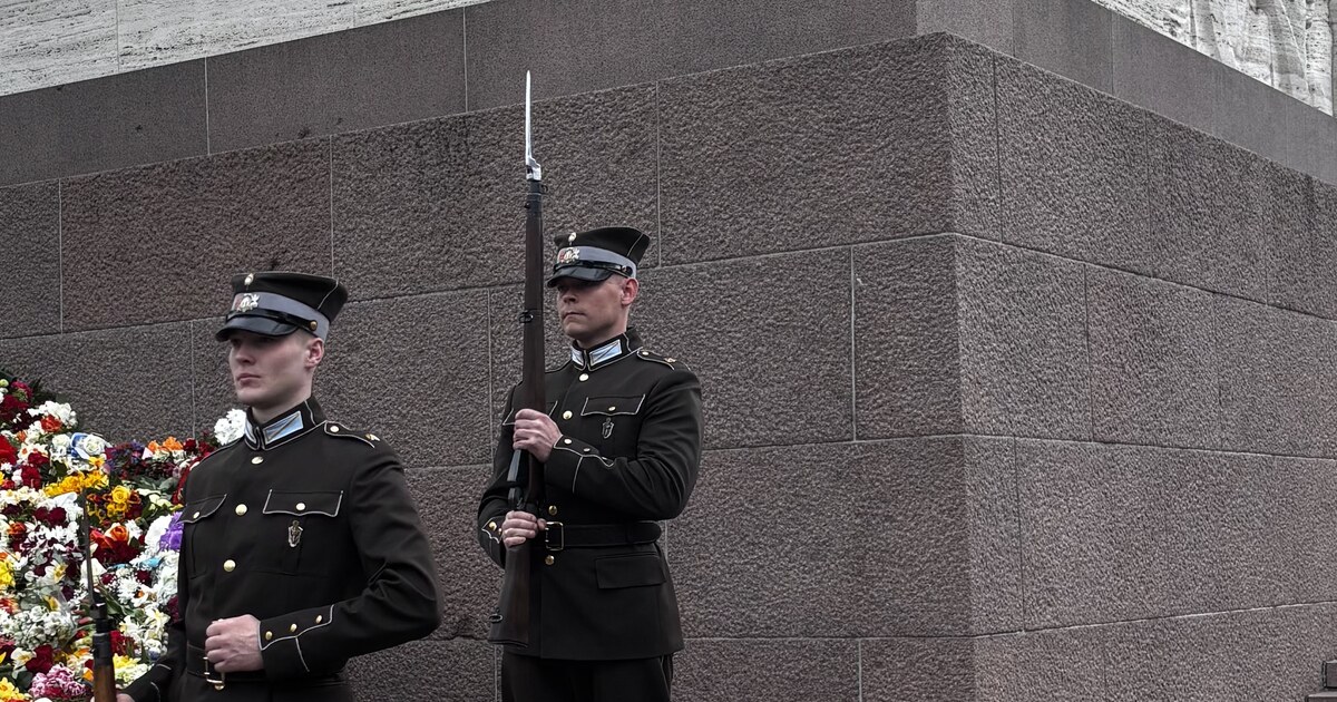 Lettiska arméns hedersvakt vid Frihetsmonumentet med en vägg av blommor lagd mot basen, Riga, på dagen för återställd självständighet