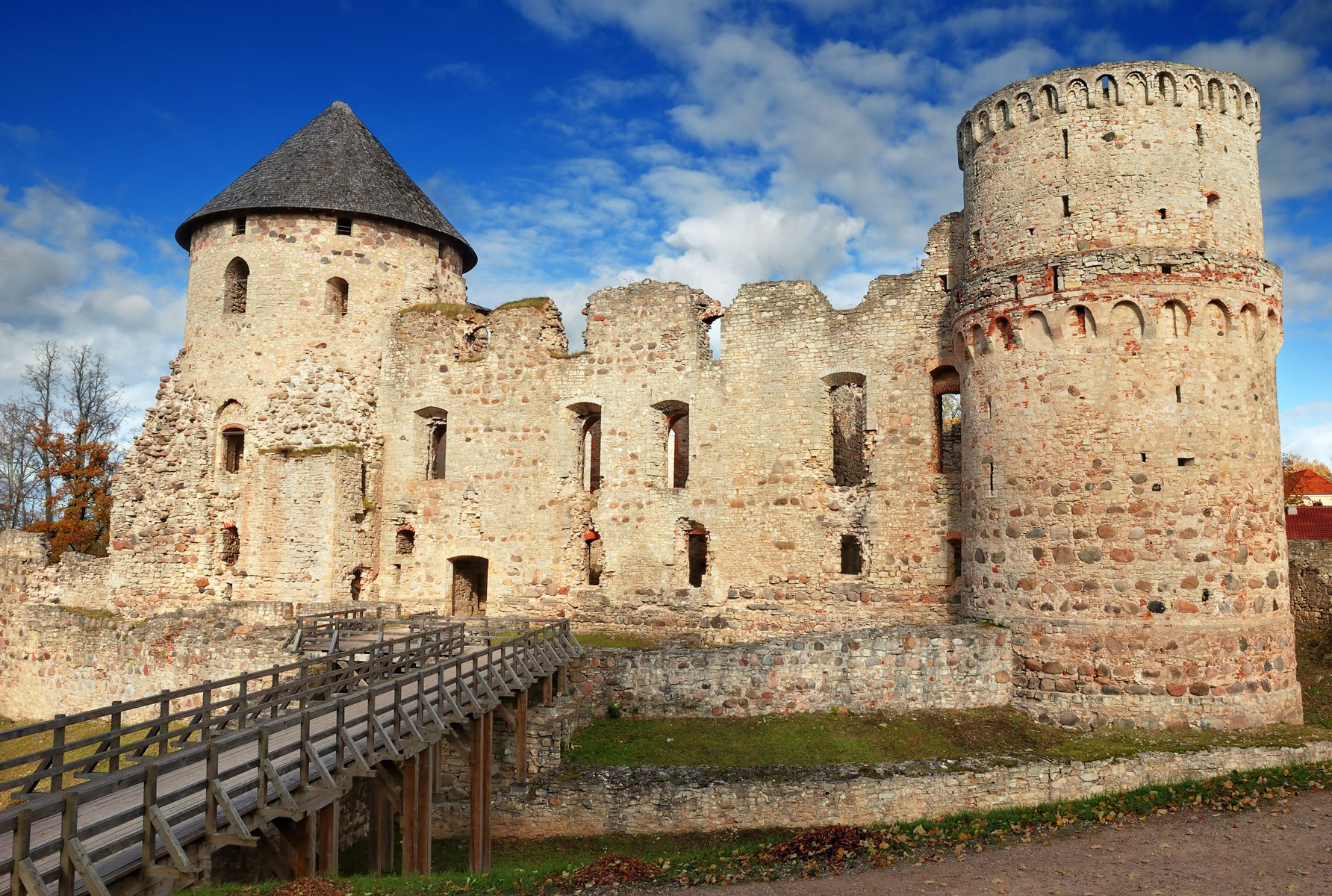 Exteriör av den medeltida ruinen Cēsis slott, röda tegelmurar i höstljus, Lettland