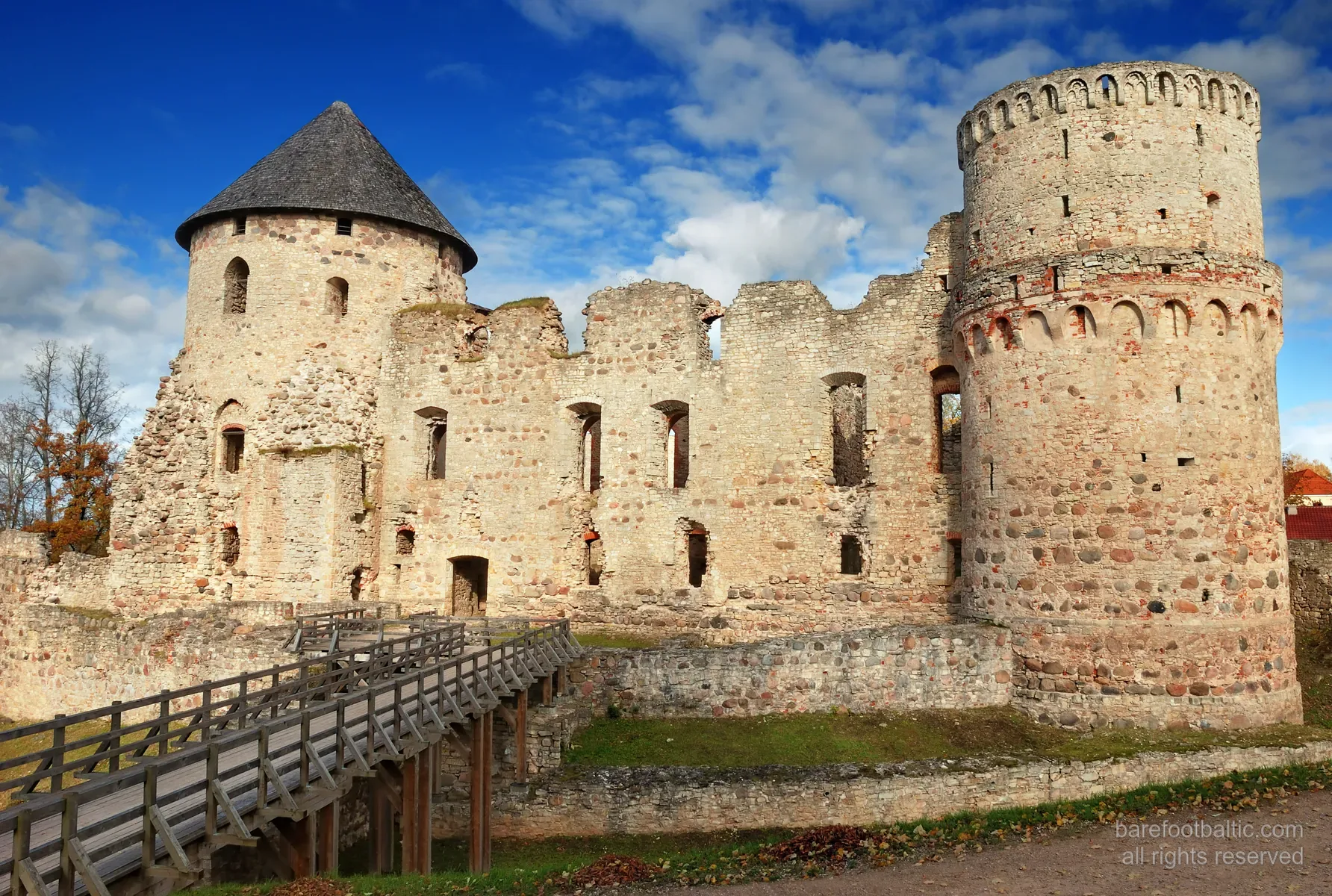 Exteriör av den medeltida ruinen Cēsis slott, röda tegelmurar i höstljus, Lettland