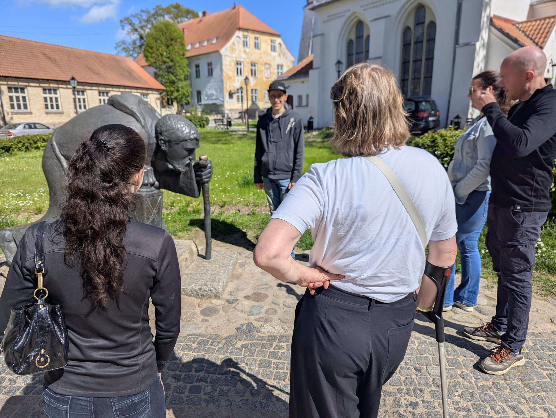 Grupp runt bronsskulpturen av pilgrimen i Cēsis gamla stan