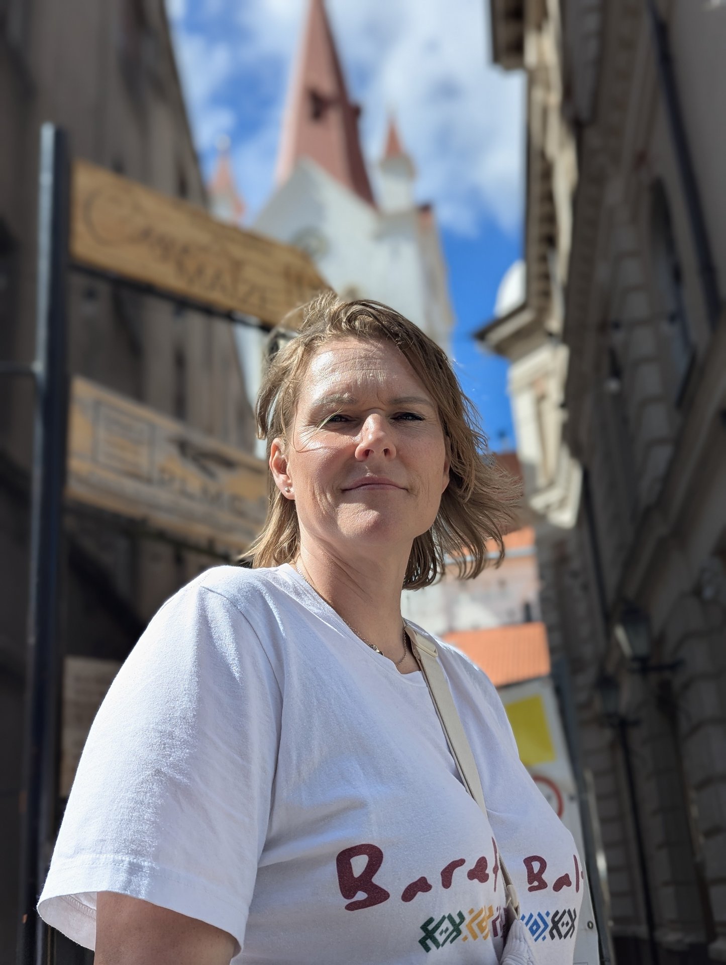 Daiga i en Barefoot Baltic-t-shirt, i bakgrunden kyrktornet i Cēsis gamla stan