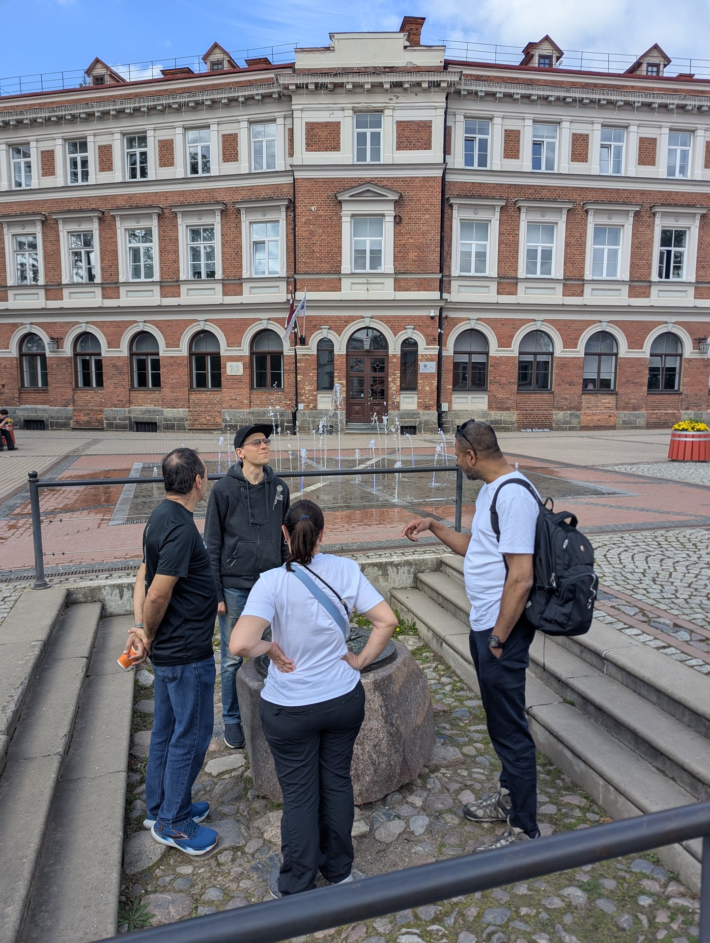 Grupp vid fontänerna på Vienības laukums, Cēsis gamla stan
