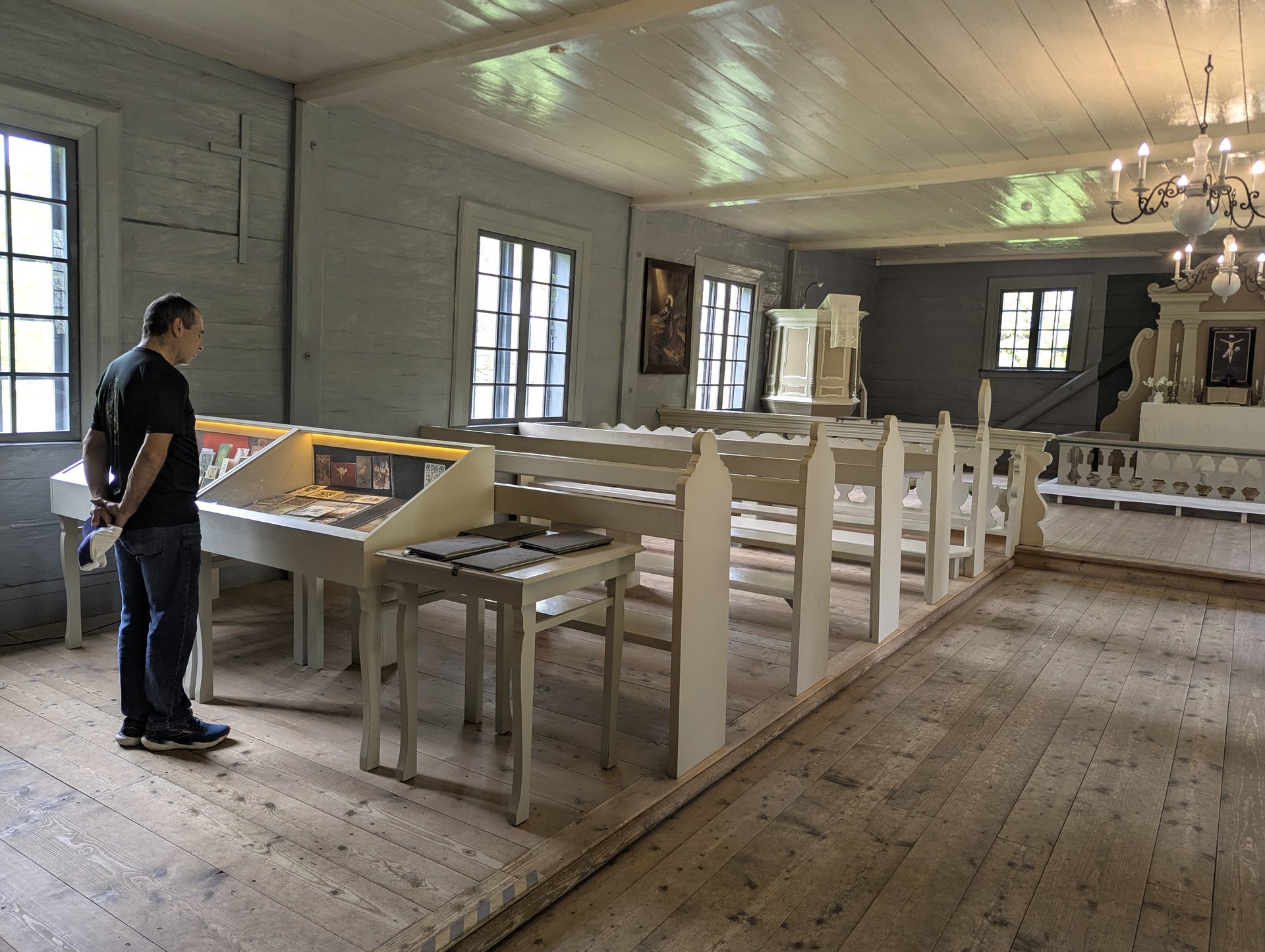 Interiör i Vidzemes trä-kyrkmuseum med en besökare framför montrarna