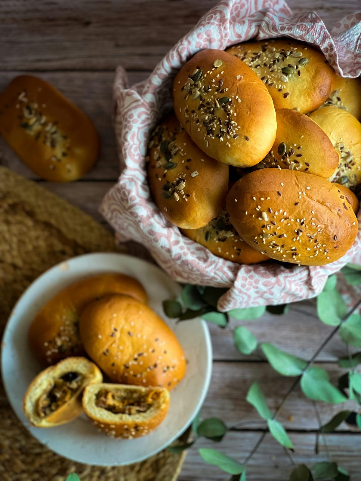 En korg med gyllene lettiska pīrāgi beströdda med frön, traditionella små fyllda bullar